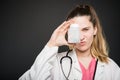 Attractive female doctor covering eye with bottle of pills Royalty Free Stock Photo