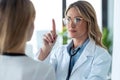 Attractive female doctor ophtalmologist checking the eye vision of beautiful young woman in consultation