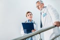 attractive female doctor showing clipboard to serious male colleague on staircase Royalty Free Stock Photo