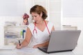 Attractive female doctor working at desk with laptop.