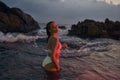 Attractive female enjoys serene night dip in ocean, red illumination enhancing beauty, travel in aquatic settings. Woman