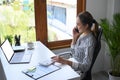 Attractive female manager sitting at modern office and talking on mobile phone. Royalty Free Stock Photo