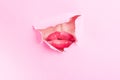 Attractive female mouth sharing a kiss thru ripped paper hole Royalty Free Stock Photo