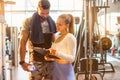 Female personal trainer showing exercise progress to male client at gym Royalty Free Stock Photo