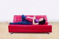 Attractive female on red sofa reading e-book at home