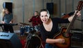 Attractive female soloist playing guitar and singing with her music band in sound studio Royalty Free Stock Photo