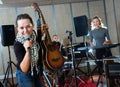 Attractive female soloist playing guitar and singing with her music band in sound studio Royalty Free Stock Photo