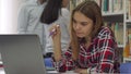 Female student keeps pen in her mouth at the library Royalty Free Stock Photo