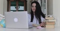 Attractive female student notes compendium from a laptop at table in a room