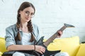 attractive female teenager playing electric guitar on sofa Royalty Free Stock Photo