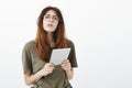 Attractive female volunteer checking guest list with gadget. Studio portrait of focused smart caucasian woman in trendy