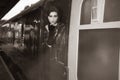 Attractive female wearing vintage evening dress leaning out of window of steam train and blowing a kiss