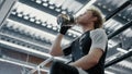 Attractive fighter drinking water in fitness center. Sportsman quenching thirst Royalty Free Stock Photo