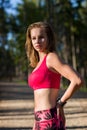 Attractive fit athletic woman standing in a forest, sweating and taking a break from workout. Royalty Free Stock Photo