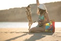 Attractive fit trendy modern hipster woman playing with straw puppy dog on beach Royalty Free Stock Photo