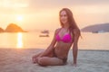 Attractive fit young brunette woman wearing bikini sitting on sea beach at sunset Royalty Free Stock Photo