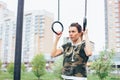 Attractive fit young woman in military colored sport wear girl pulls up on the rings at the street workout area. The healthy Royalty Free Stock Photo