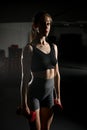 Attractive fit young woman works out with dumbbellsin gym, dark background. Royalty Free Stock Photo