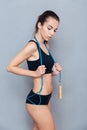 Attractive fitness girl holding skipping rope over grey background Royalty Free Stock Photo