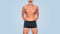 Attractive fitness male model in black underwear showing his abdominal torso on a blue background. Image of sporty handsome strong