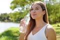 Attractive fitness woman looking away holding a bottle of water to drink in city park Royalty Free Stock Photo