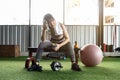 Attractive fitness woman sitting on a chair and resting after workout at fitness centre. Female take a break after hard