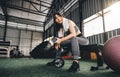 Attractive fitness woman sitting on a chair and resting after workout at fitness centre. Female take a break after hard