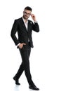 Formal businessman walking with hand in pocket fixing glasses