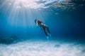 Attractive free diver with white fins glides and posing underwater in blue ocean with sunlight. Girl dive underwater Royalty Free Stock Photo