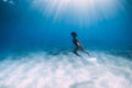 Attractive free diver with white fins glides and posing underwater in blue ocean with sunlight. Girl dive underwater Royalty Free Stock Photo