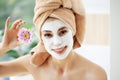 Attractive funny woman with a clay mask on her face.