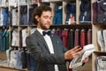 Young hansome brunette man choosing item in boutique.