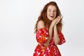 Attractive ginger girl with long curly hairstyle, posing in floral summer dress, laughing and smiling and gazing aside