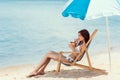 attractive girl in bikini drinking coconut cocktail in beach chair