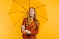 An attractive girl, in a bright yellow dress and an autumn jacket, stands with a yellow umbrella on a yellow background. Autumn Royalty Free Stock Photo