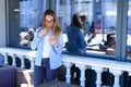 Attractive girl browsing by phone and standing at cafe.