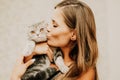 Attractive young woman with long hair embracing her pet with smile. Indoor portrait of cute woman playing with cat Royalty Free Stock Photo