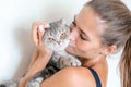 Attractive young woman with long hair embracing her pet with smile. Indoor portrait of cute woman playing with cat Royalty Free Stock Photo