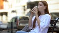 Attractive girl enjoying taste and aroma of warm sweet coffee in paper glass