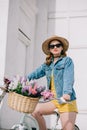 attractive girl in hat sunglasses and denim jacket looking at camera and riding bicycle Royalty Free Stock Photo