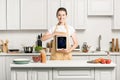 attractive girl holding ipad in kitchen and looking