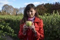 Attractive girl holds fresh green apple in her hand standing in the autumn park Royalty Free Stock Photo