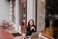 Attractive girl with laptop and cup of coffee is sitting outside of cafe. Young business woman with laptop is working Royalty Free Stock Photo