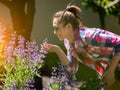 Young woman smelling violet flowers holding hand shears in sunshine