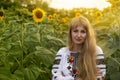 Girl with long hair in Ukrainian clother posing among the bales in the field