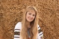 Girl with long hair in Ukrainian clother posing among the bales in the field