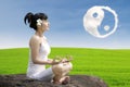 Attractive girl meditate yoga under ying yang cloud