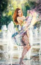 Attractive girl in multicolored short dress playing with water in a summer hottest day. Girl with wet dress enjoying fountains