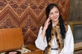 Attractive girl in national clothes sitting near aged rertro vinyl record player and looking at the right side