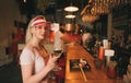 Attractive girl in a pink cap sits at a table in a sushi bar, holds a glass of wine, looks into the camera and smiles. A sweet Royalty Free Stock Photo